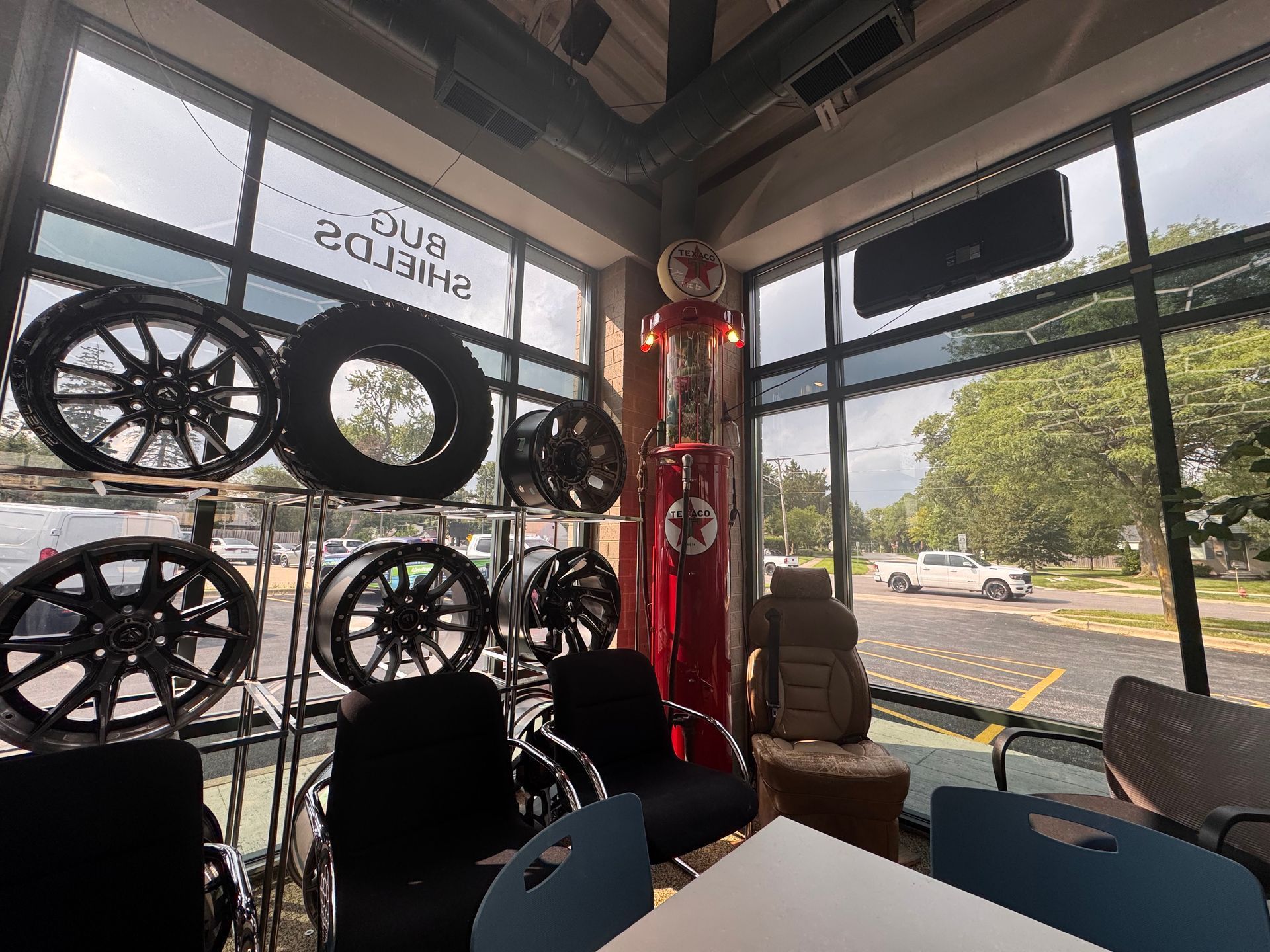 Bike shop interior with mounted wheels, red pillar, and street view through large windows.