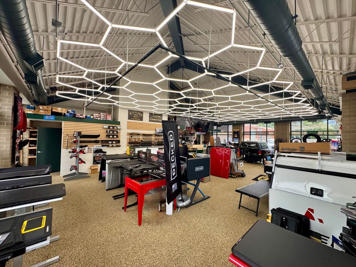 Modern showroom with hexagonal ceiling lights, furniture displays, and office equipment on carpeted floor