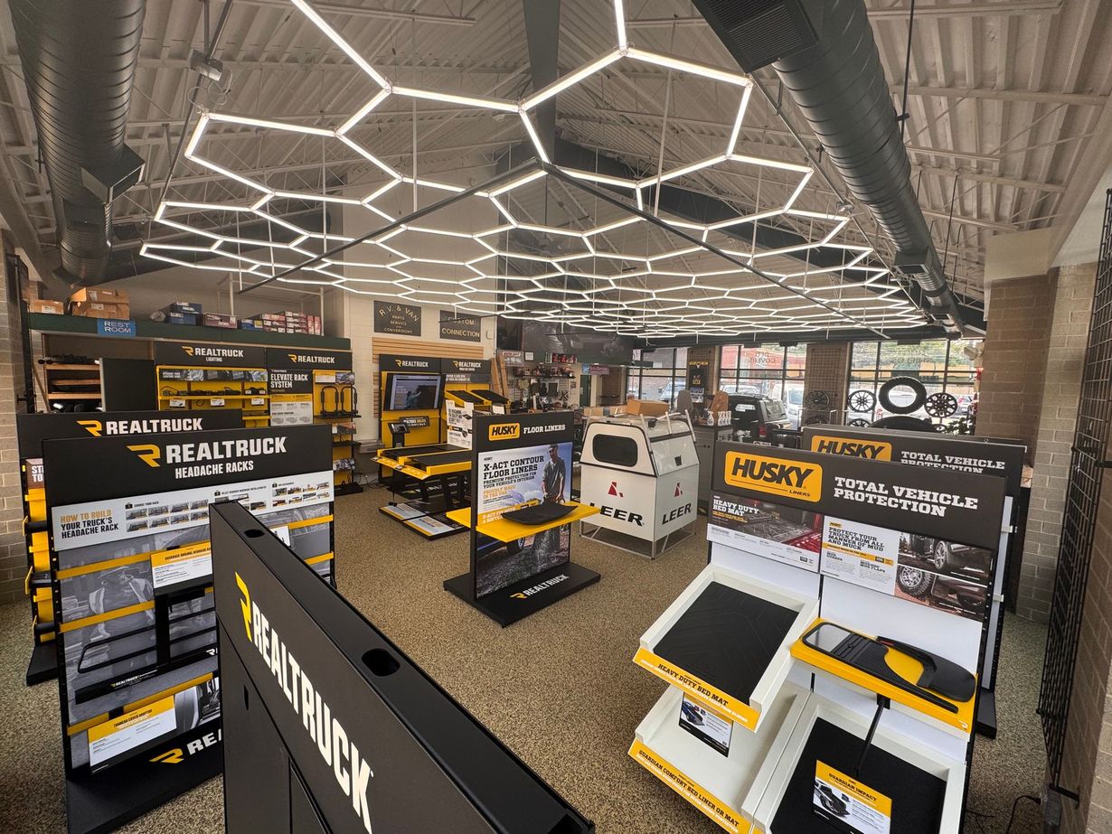 Showroom with yellow-and-black Husqvarna displays and equipment under hexagonal ceiling lights.