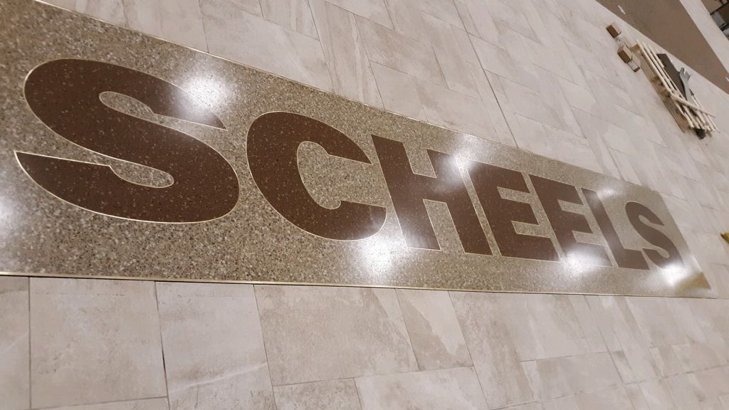 A sign on a wall that says scheels on it