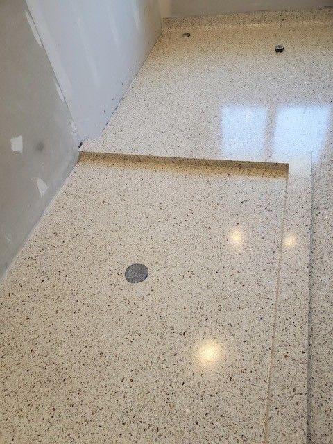 A bathroom with a marble floor and a shower stall.