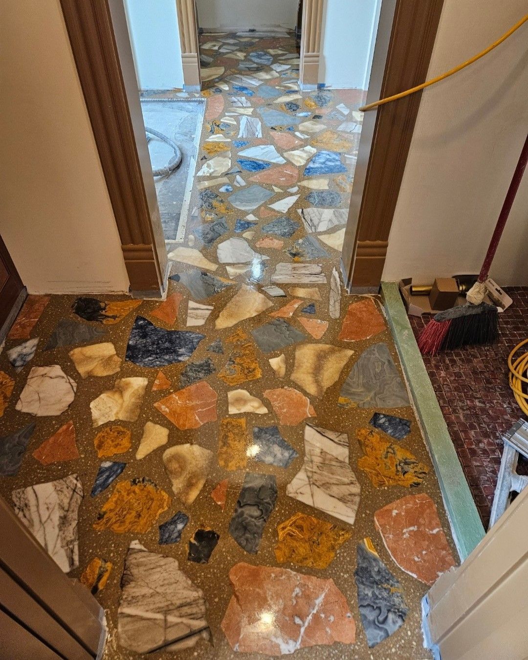 A hallway with a colorful tile floor and a broom.