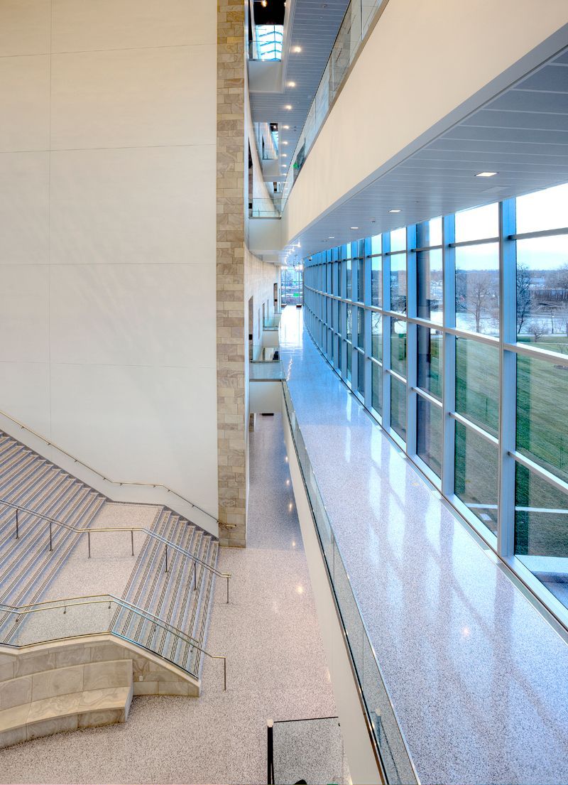 A long hallway with stairs and a lot of windows
