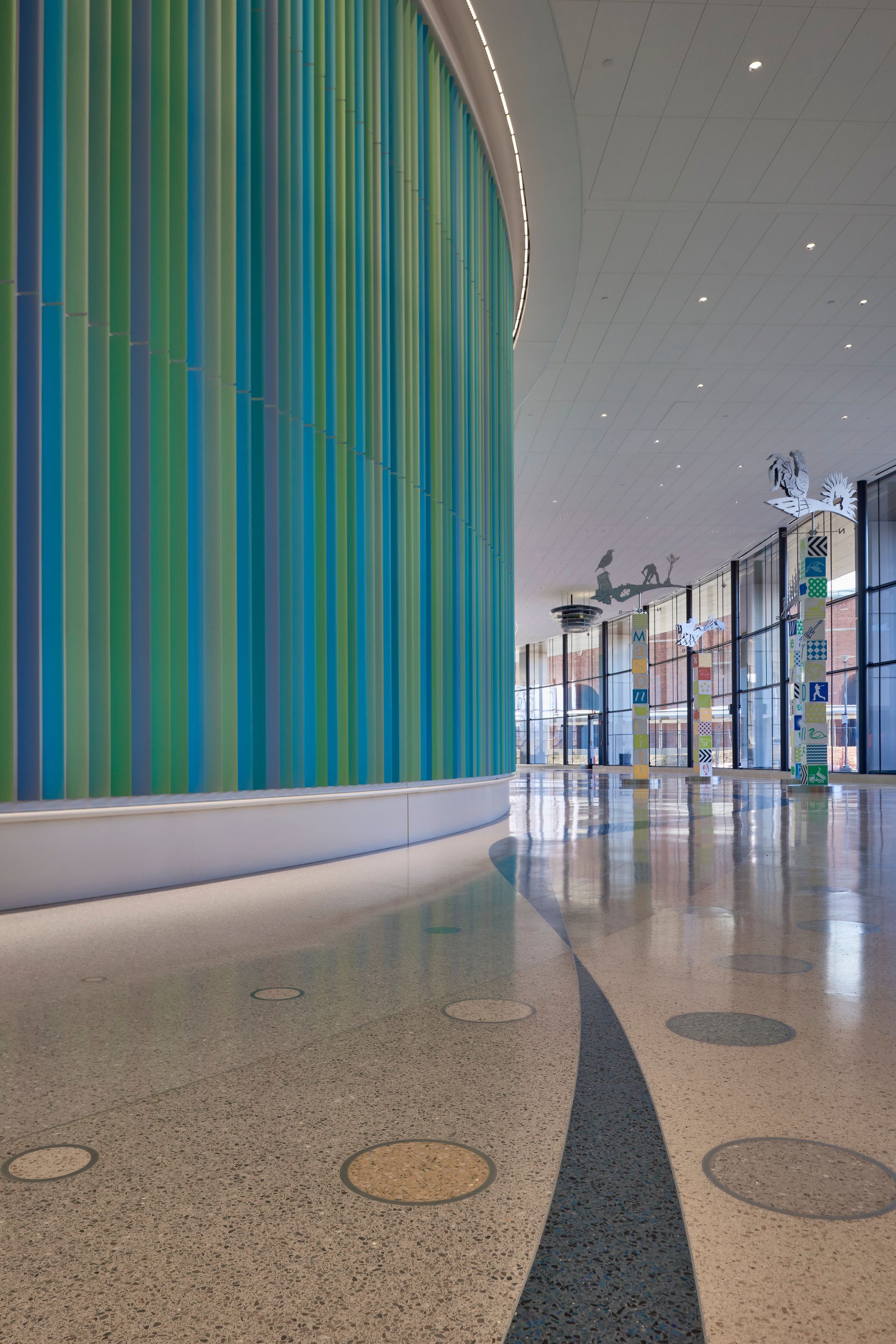 A long hallway with a colorful wall and a concrete floor.