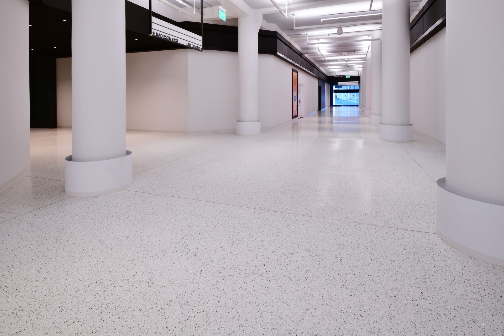 A long hallway with columns and a white floor