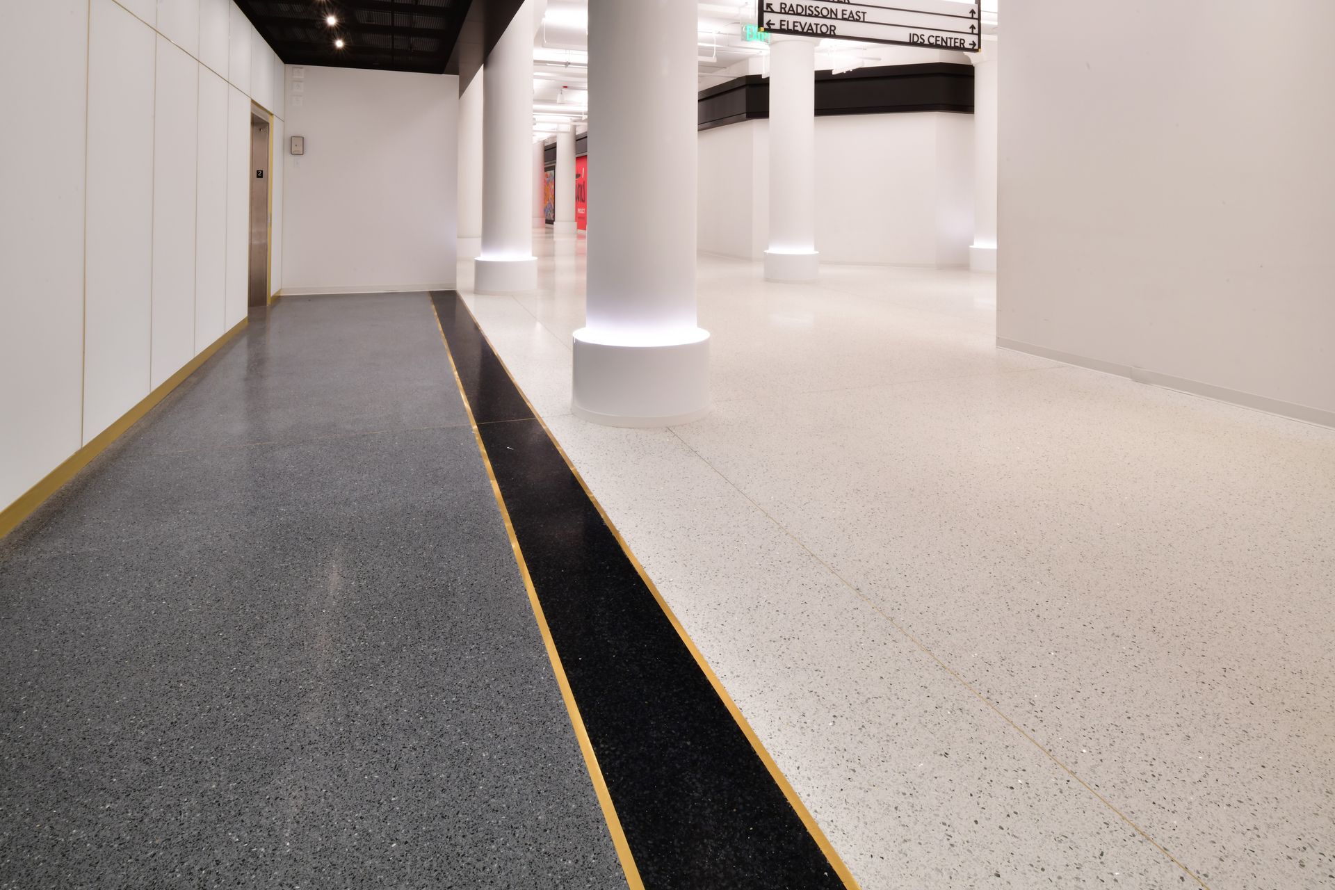 A hallway with columns and a black and white floor