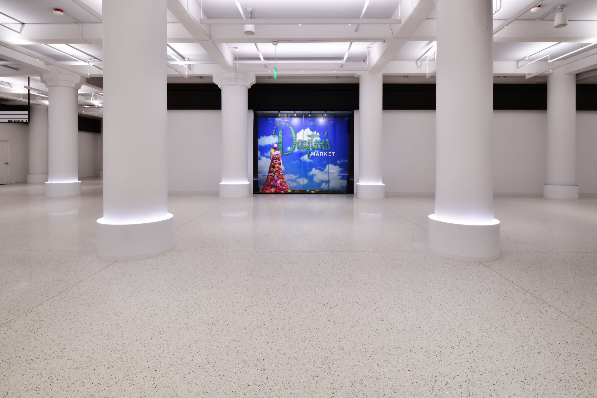 A large empty room with white pillars and a picture on the wall