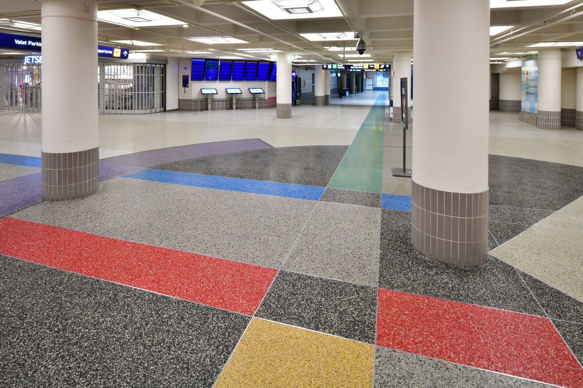 A large empty room with a colorful floor and pillars