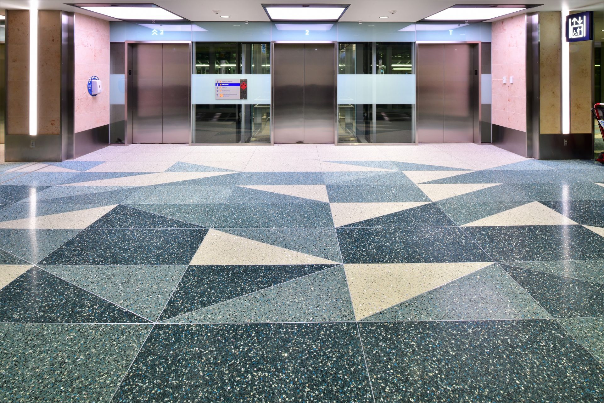 Two elevators in a building with a geometric pattern on the floor