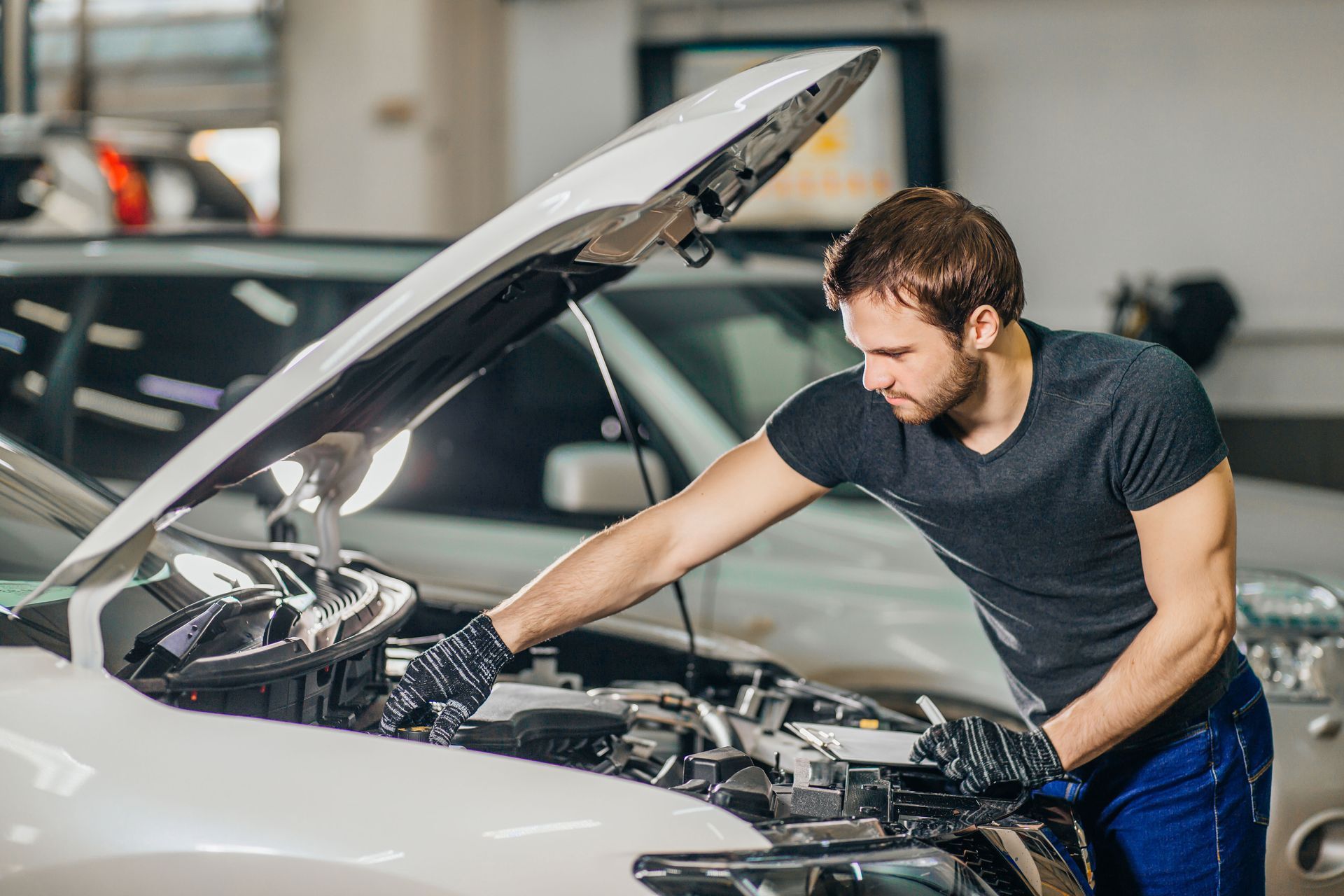 A man is working on the engine of a car in a garage.