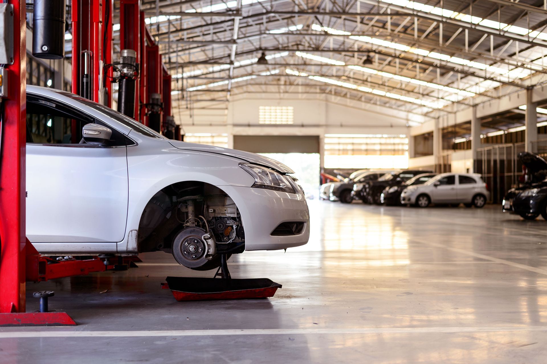 A white car is sitting on a lift in a garage.