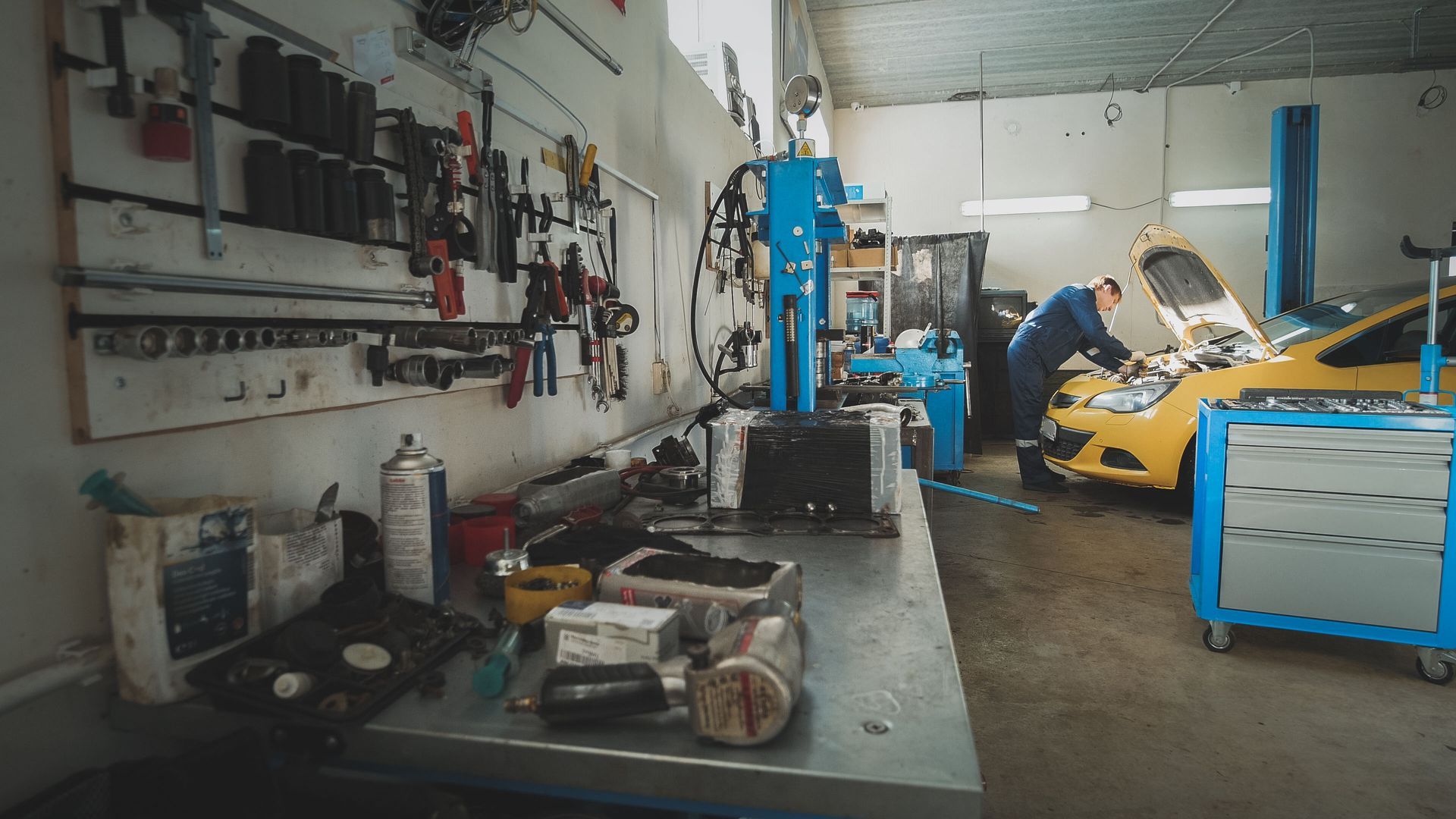 A man is working on a yellow car in a garage.