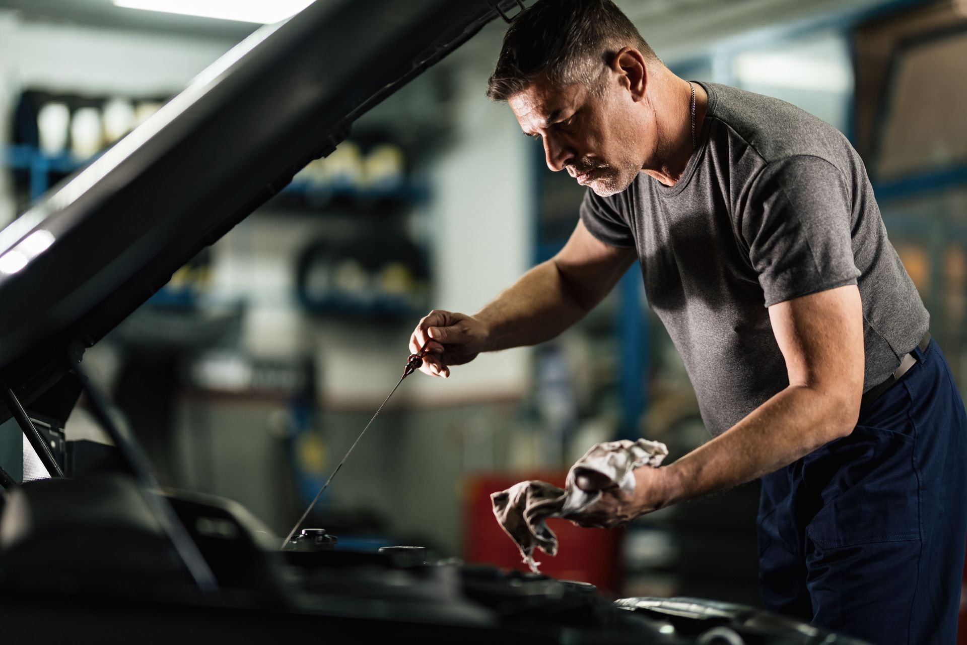 A man is checking the oil level of a car in a garage.