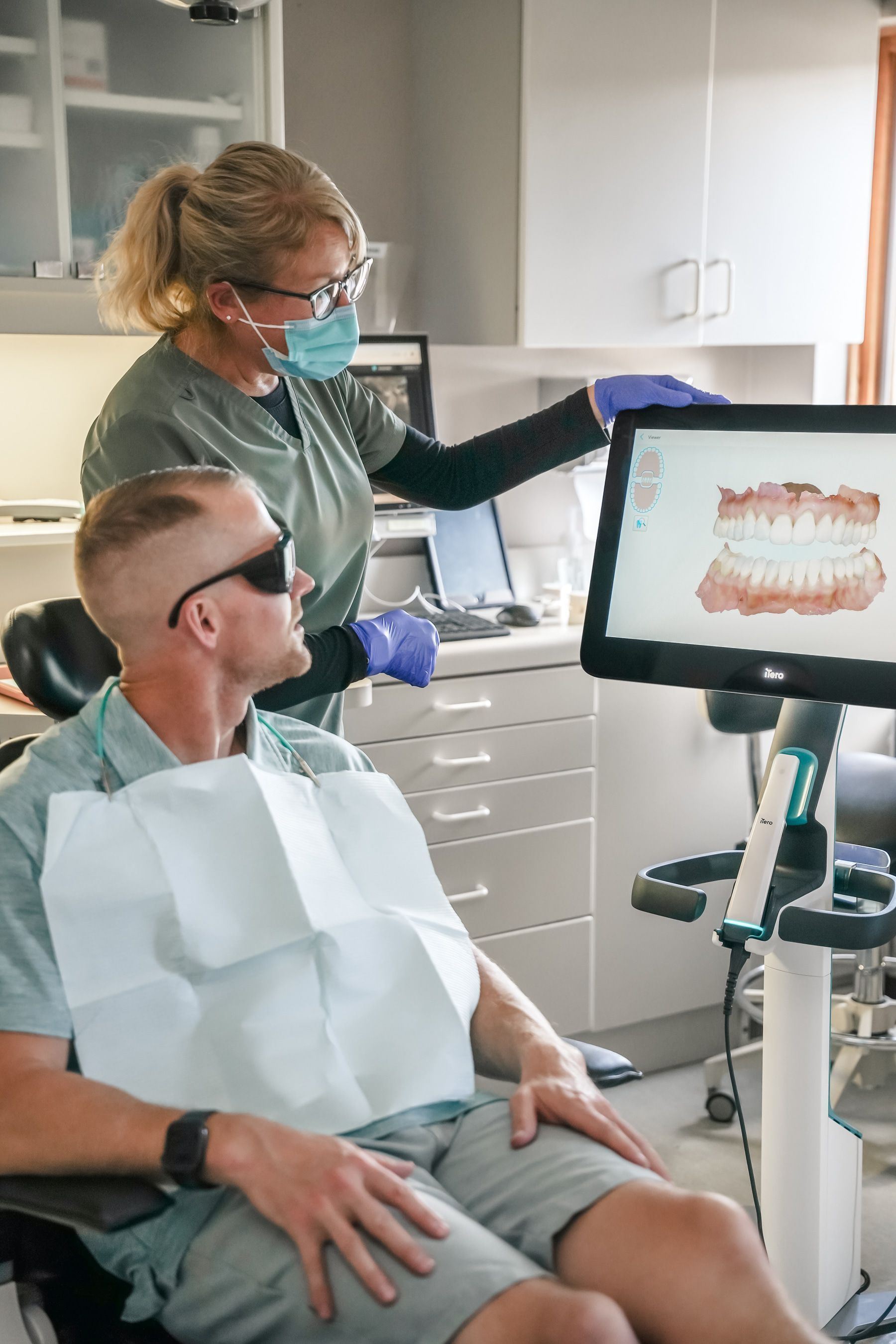 Dentist showing a patient a digital scan of his teeth on a monitor in an office.