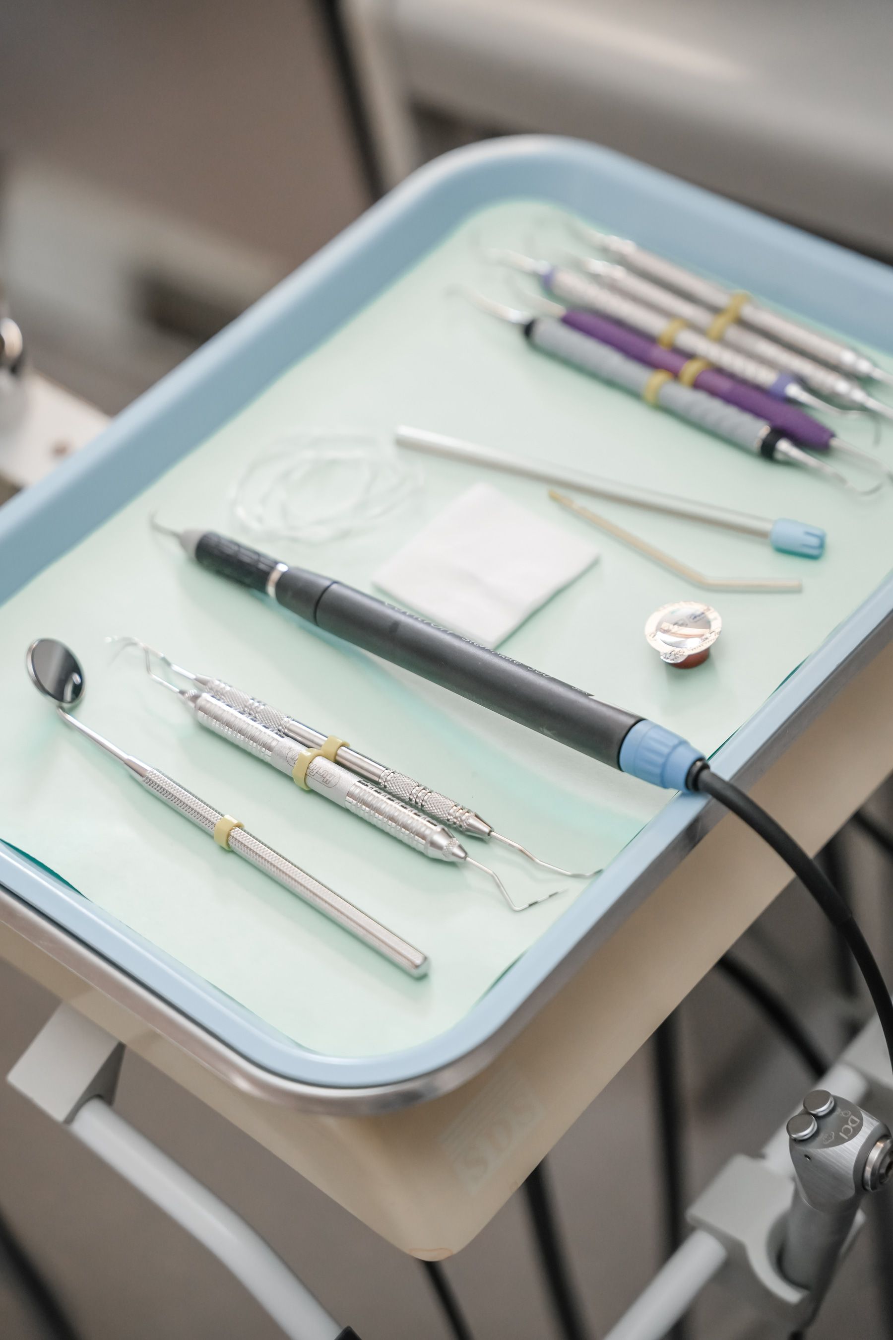 Dental tools on a tray, including a mirror, probes, and a scaler.