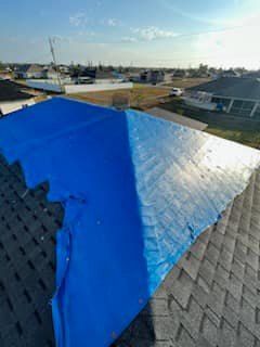 A blue tarp is covering the roof of a house.
