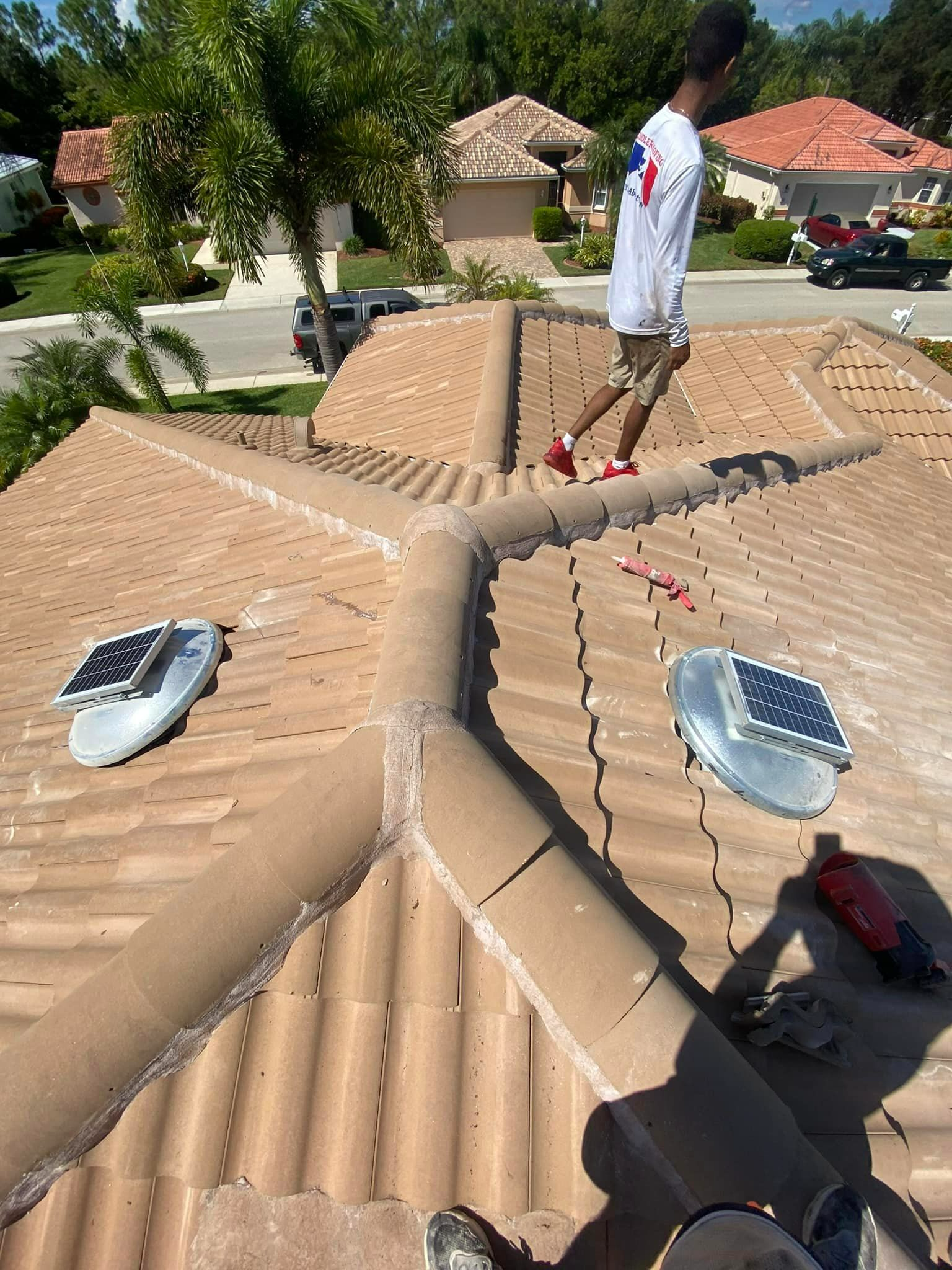 A man is standing on top of a tiled roof.