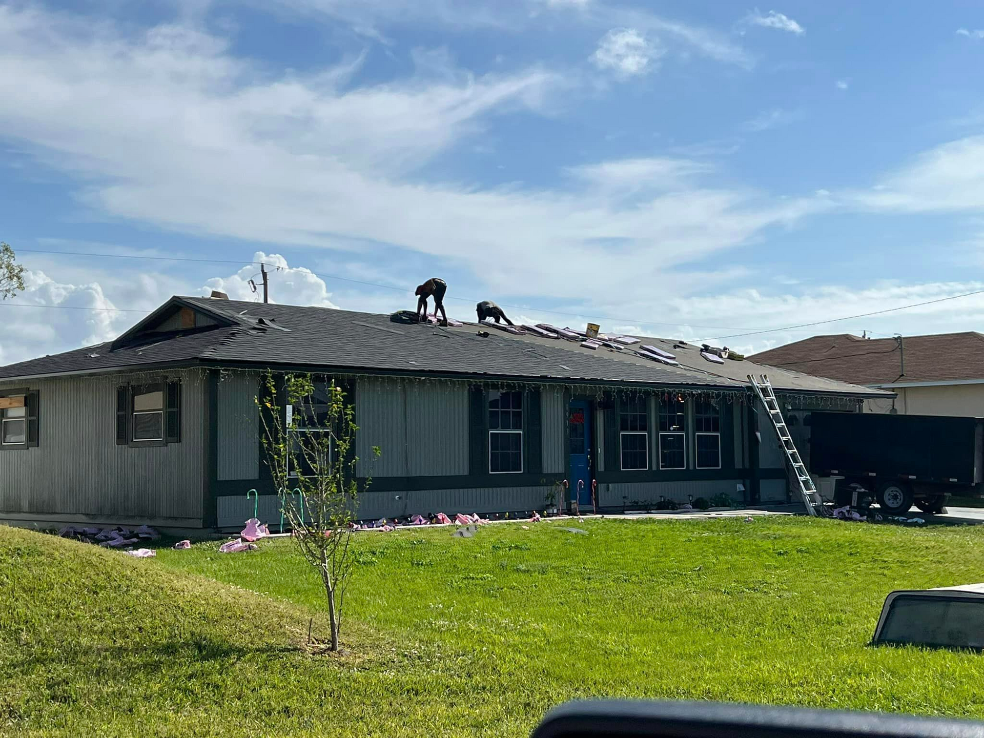 A group of people are working on the roof of a house.