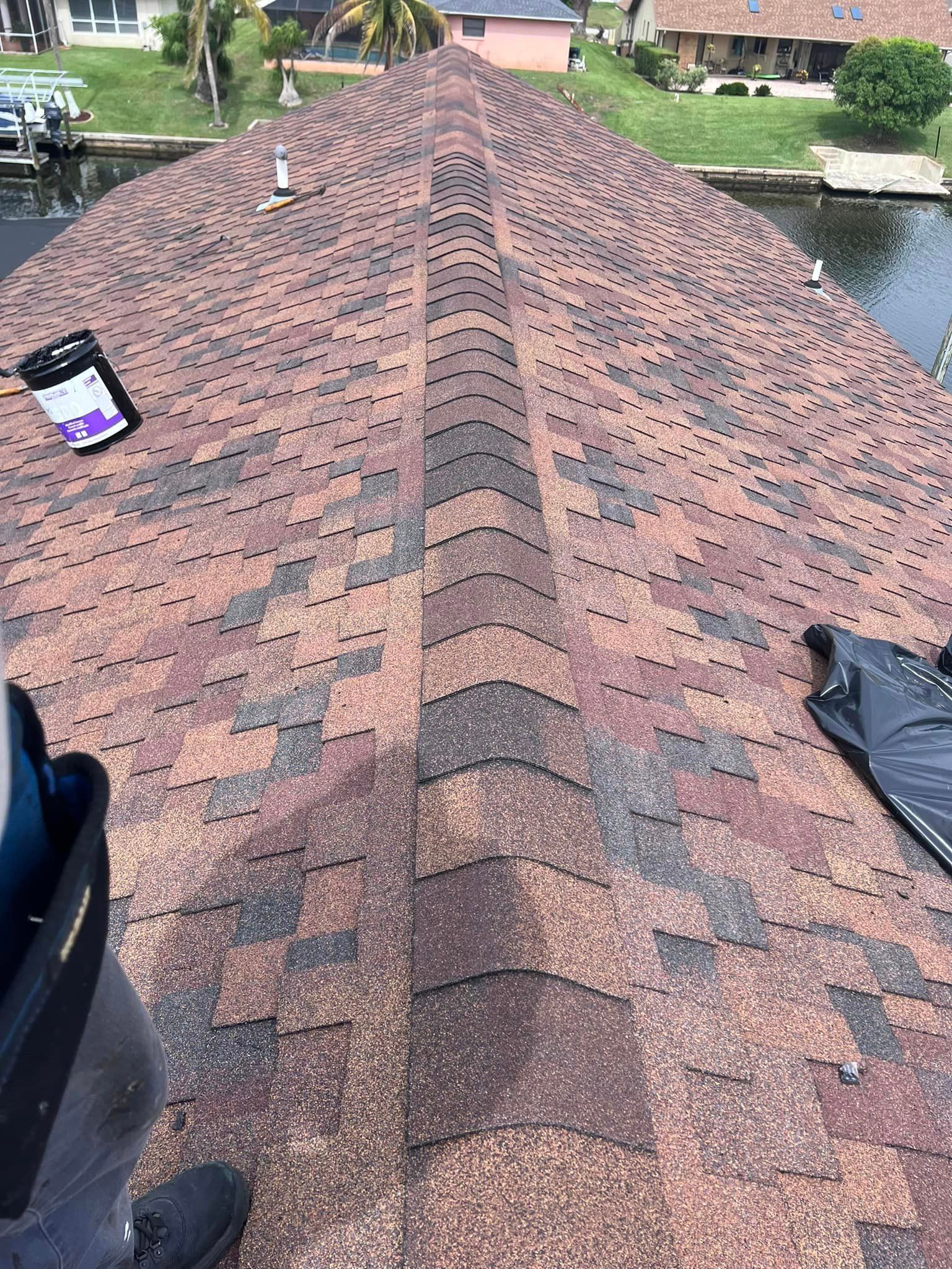 A person is standing on top of a roof next to a body of water.