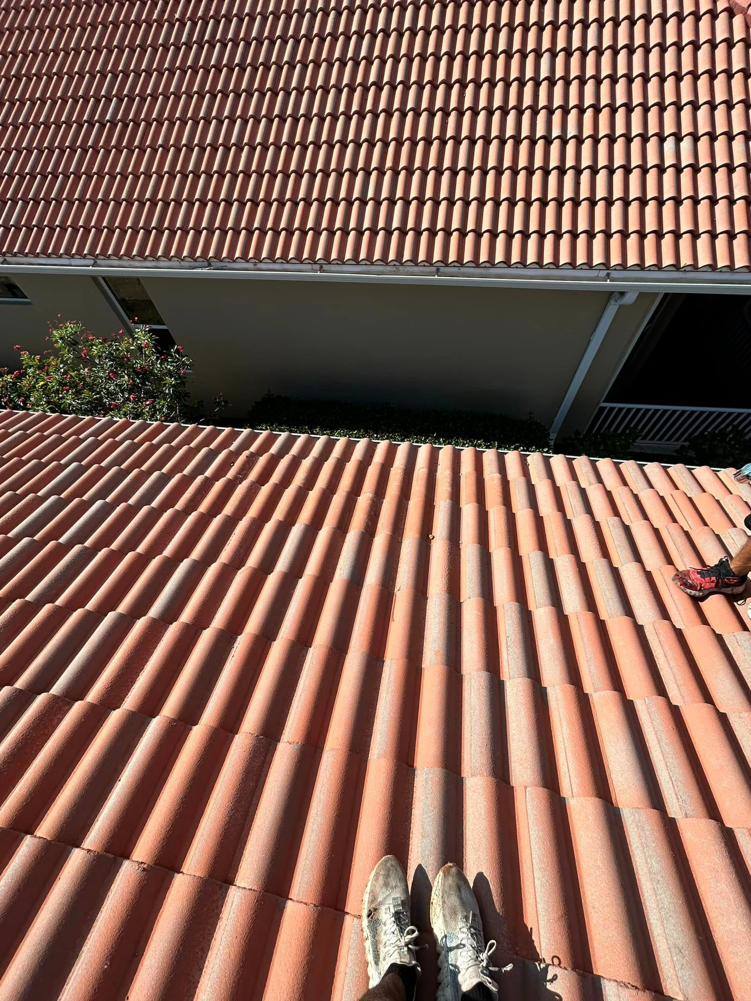 A person is standing on top of a red tiled roof.