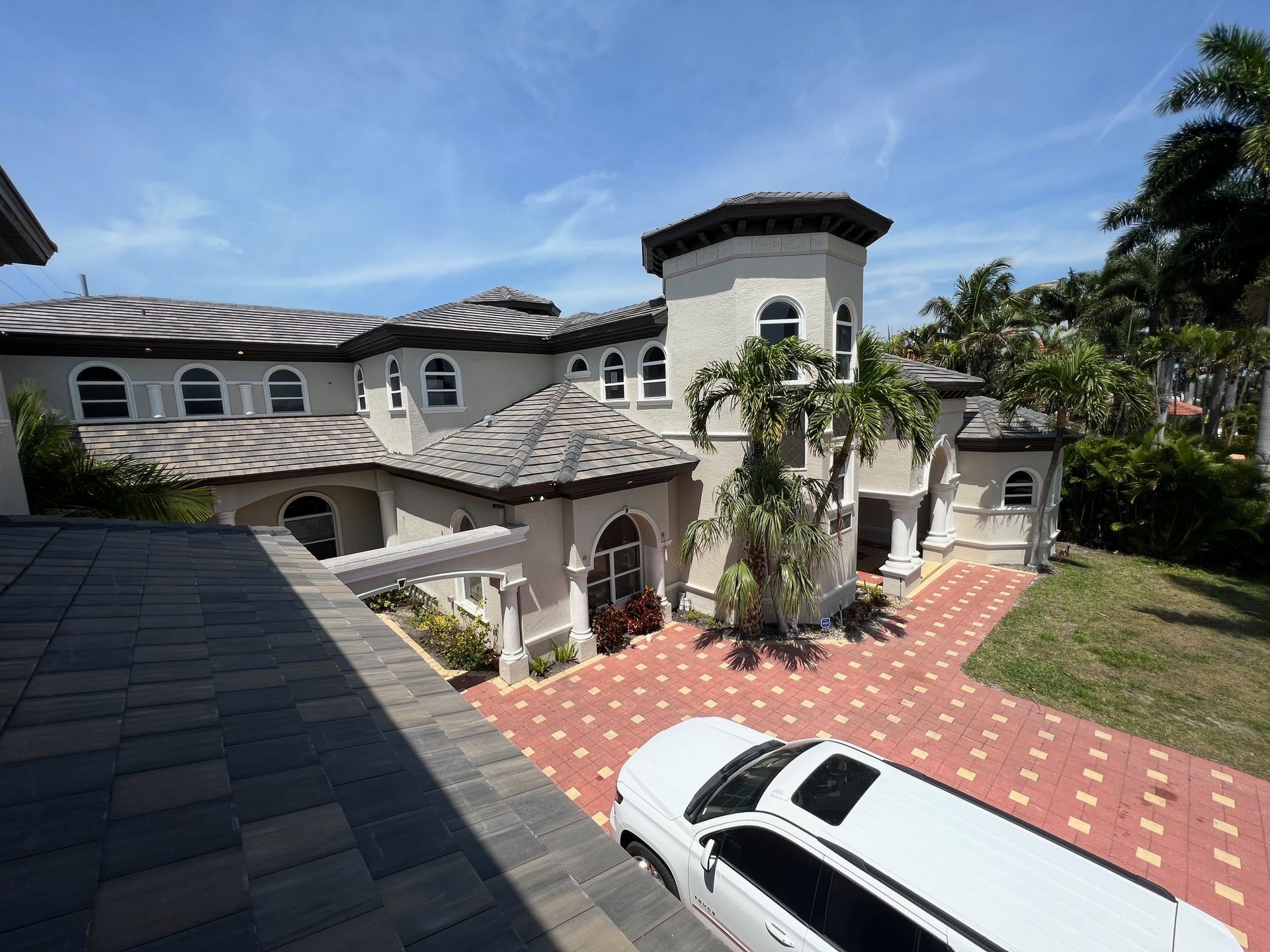 A white limousine is parked in front of a large house