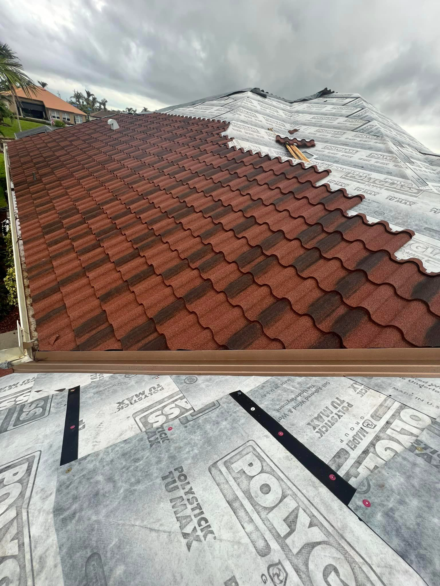 A red tile roof is being installed on a house.
