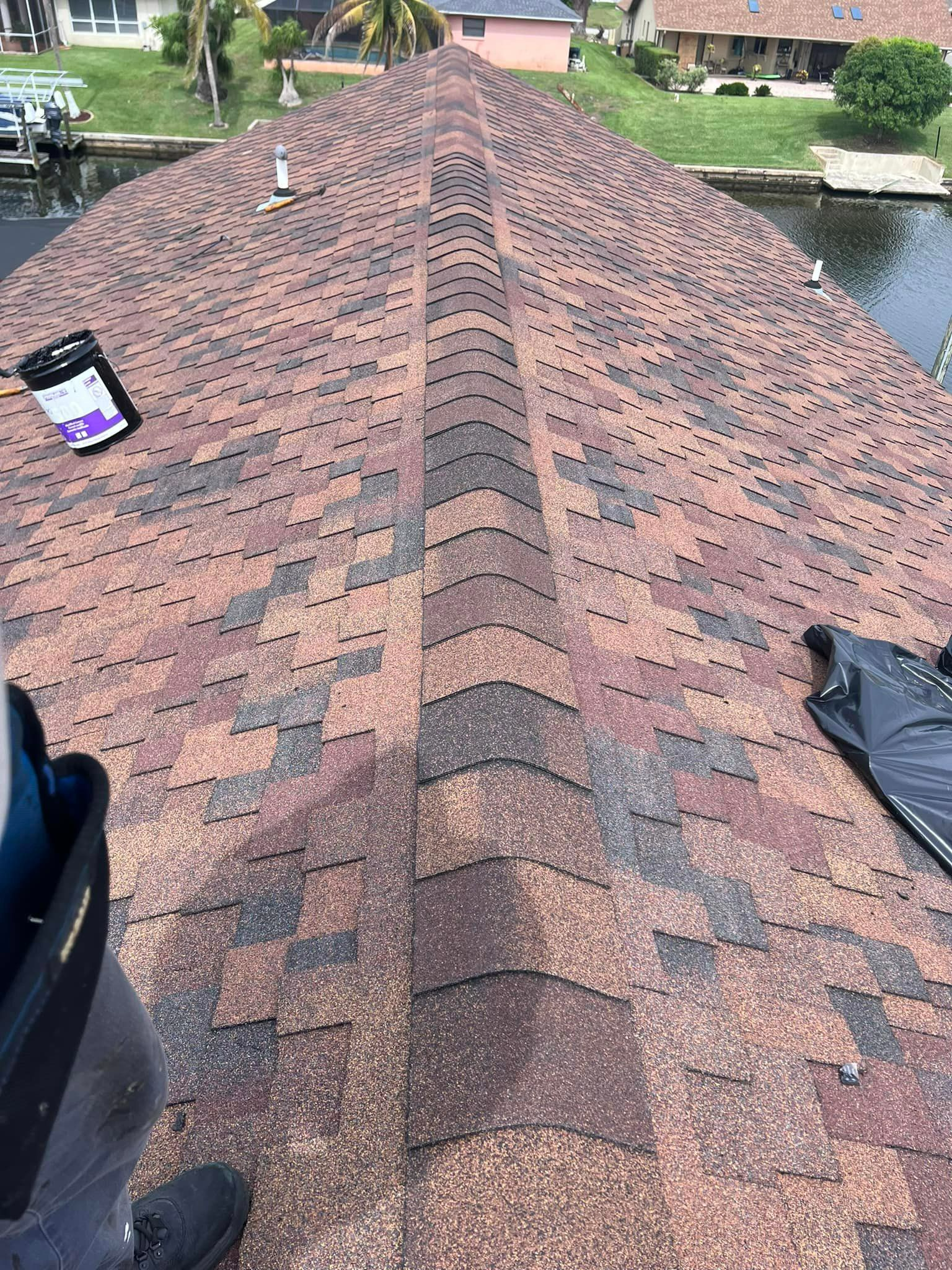 A person is standing on top of a roof next to a body of water.