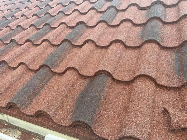A close up of a red tile roof with a gutter.