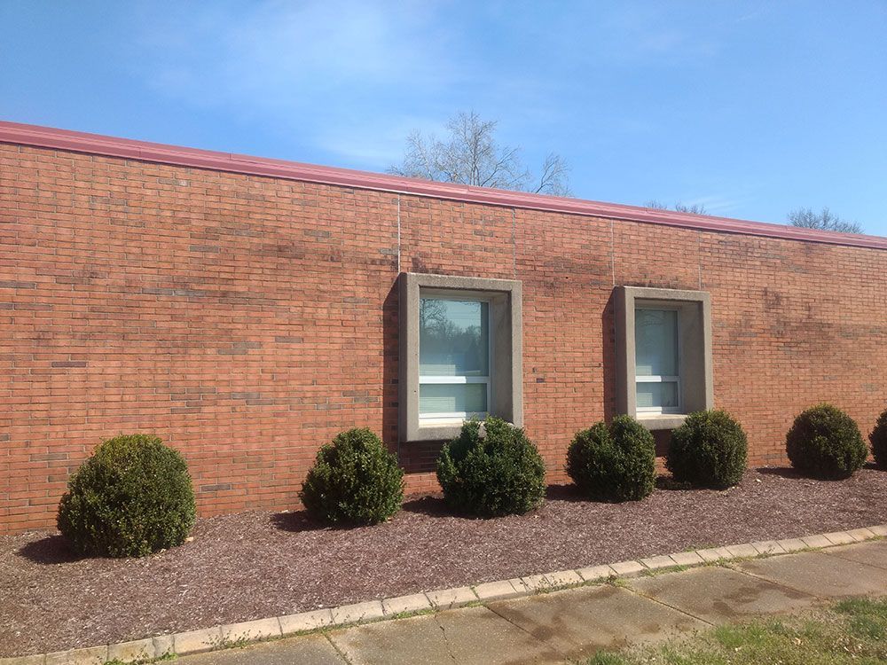 A brick building with a row of bushes in front of it.