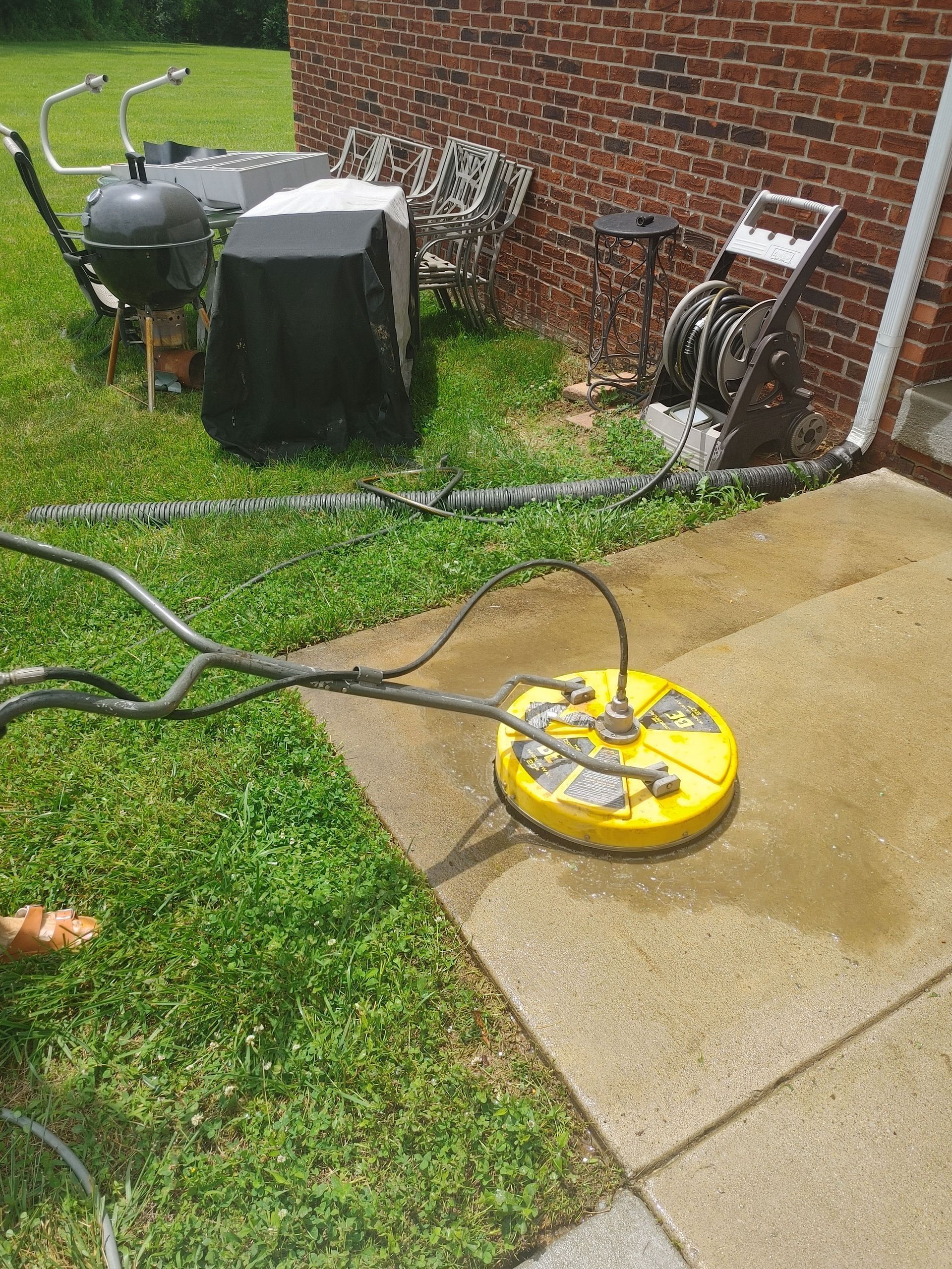 A man is cleaning a brick building with a high pressure washer.