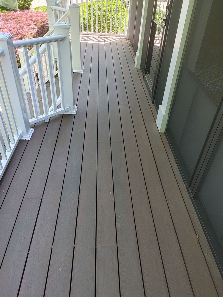 A wooden deck with a white railing and a sliding glass door.