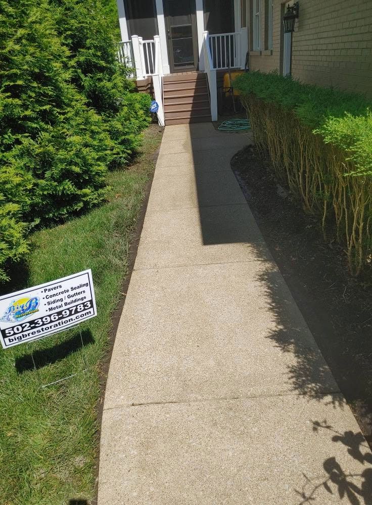 A concrete walkway leading to a house with a sign on the side of it.