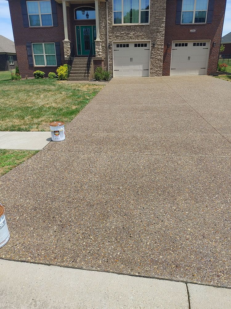 A bucket of paint is sitting on the sidewalk in front of a house.