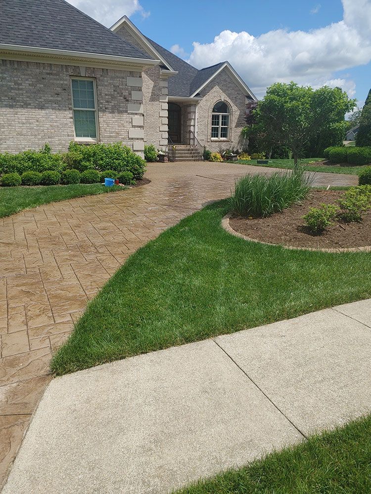 A brick house with a driveway and a sidewalk in front of it.