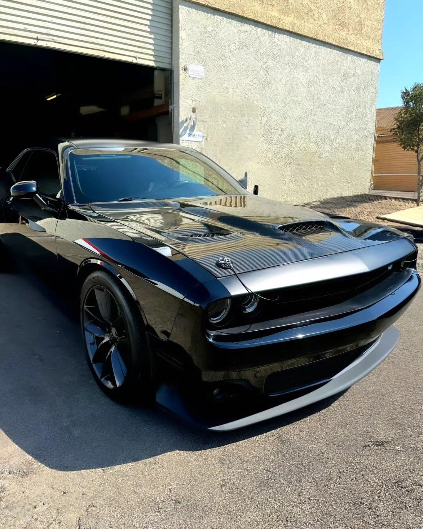 A black dodge challenger is parked in front of a building.