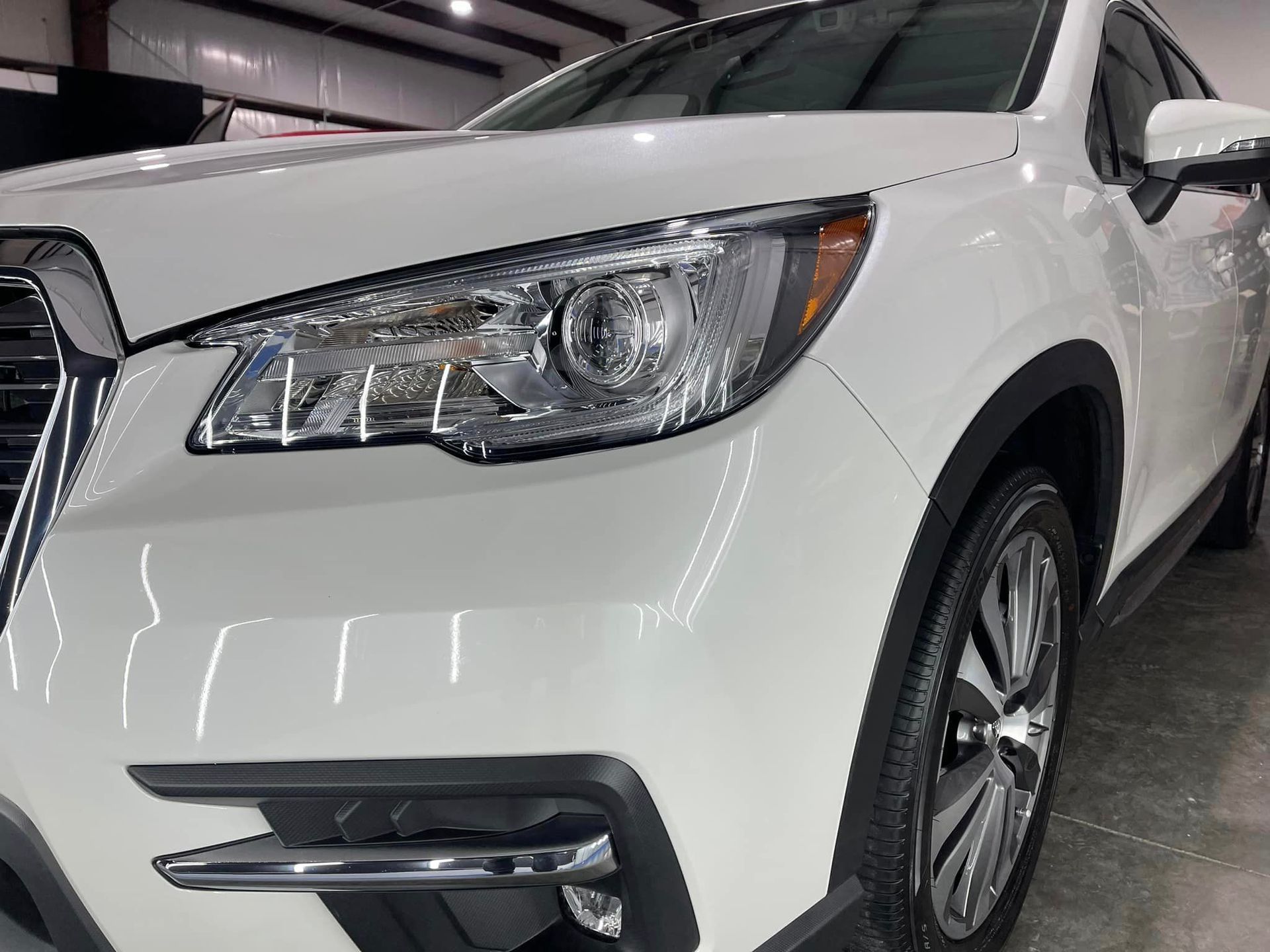 A white subaru ascent is parked in a garage.