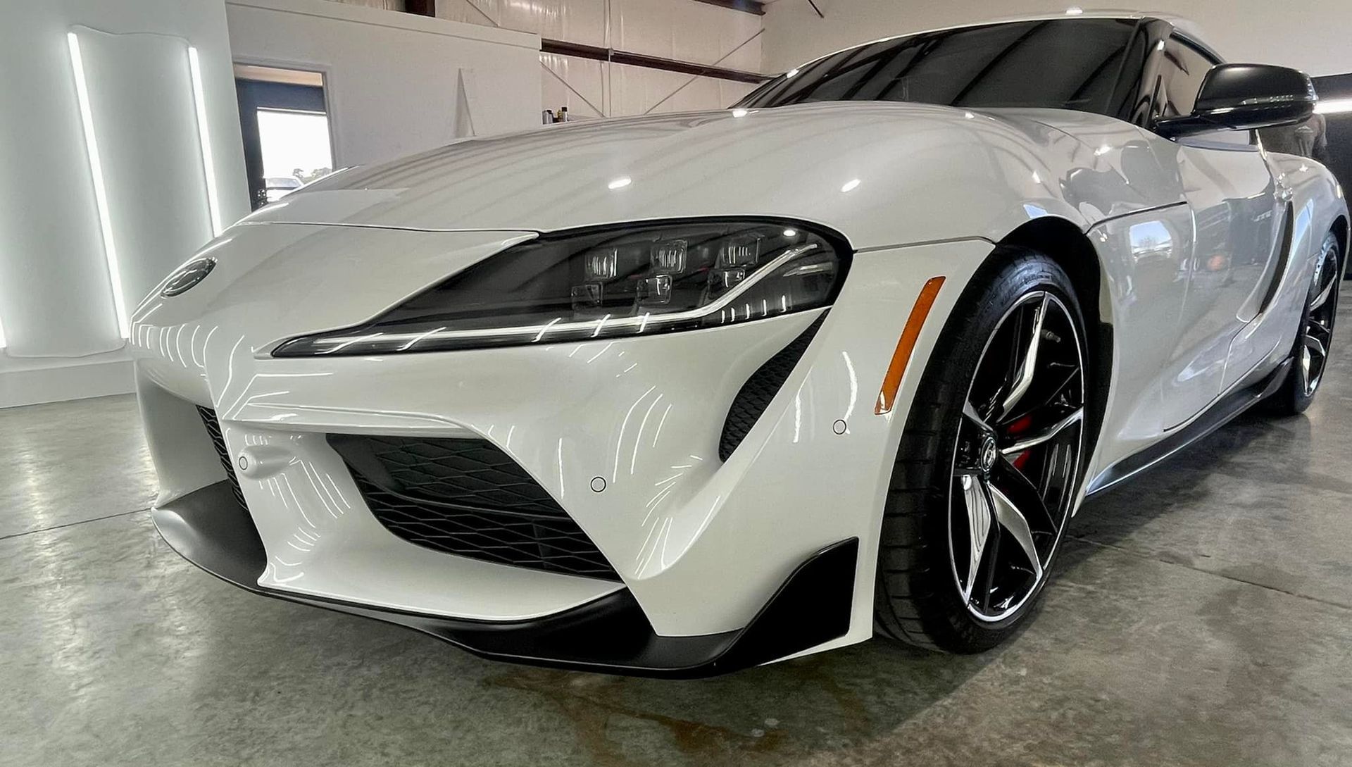 A white toyota supra is parked in a garage.