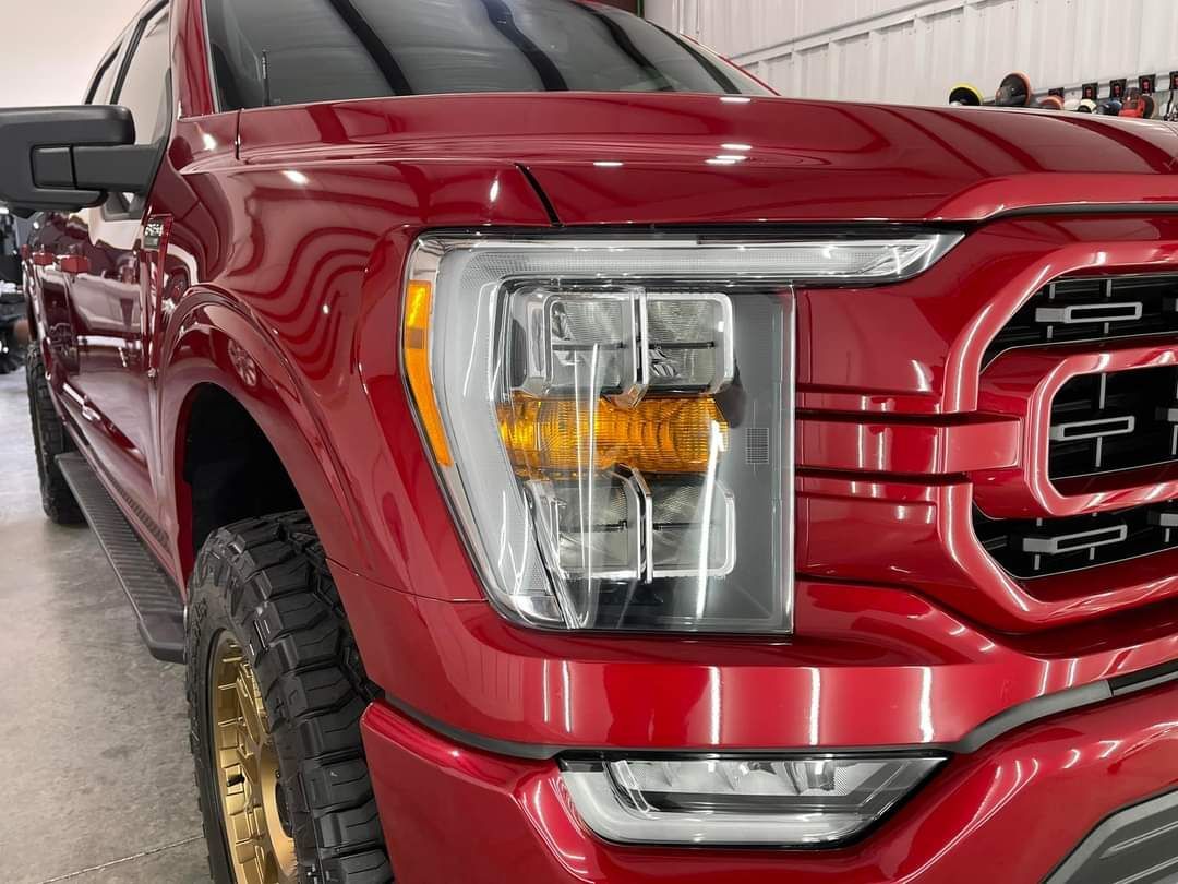 A red ford f150 truck is parked in a garage.