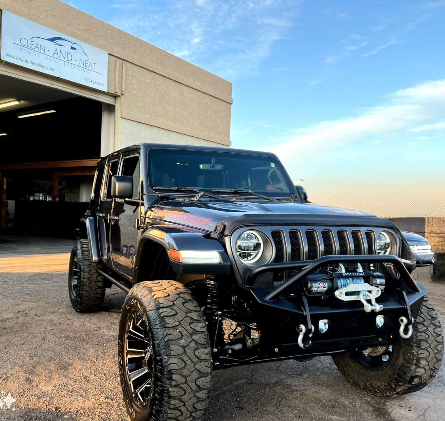 A black jeep is parked in front of a building