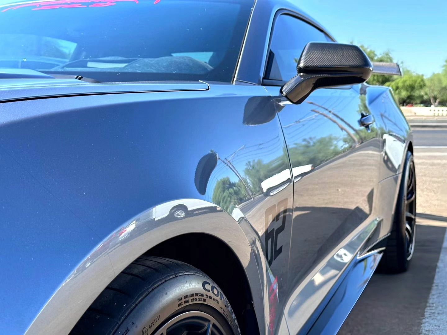 A blue sports car is parked on the side of the road.