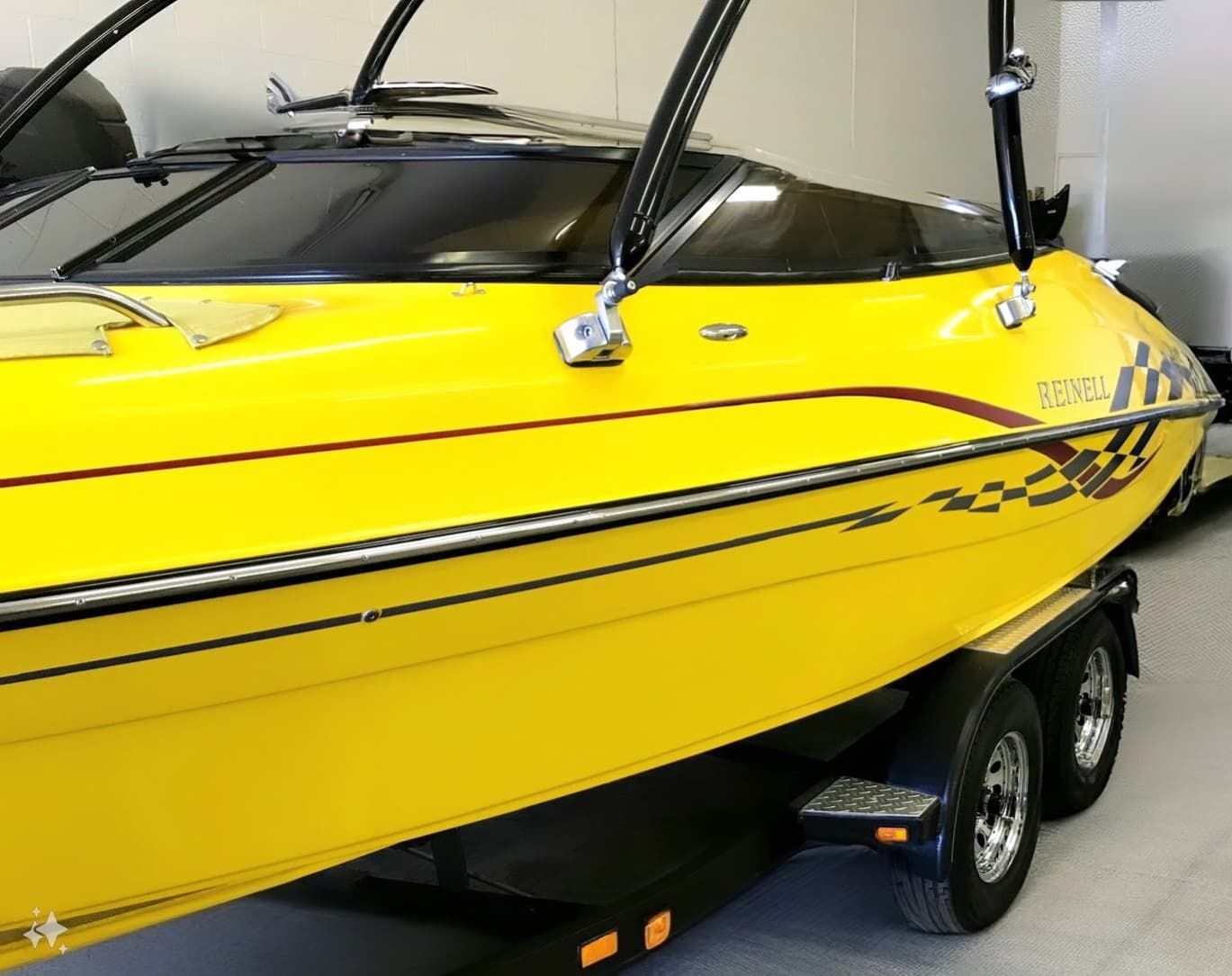A yellow boat is parked on a trailer in a garage