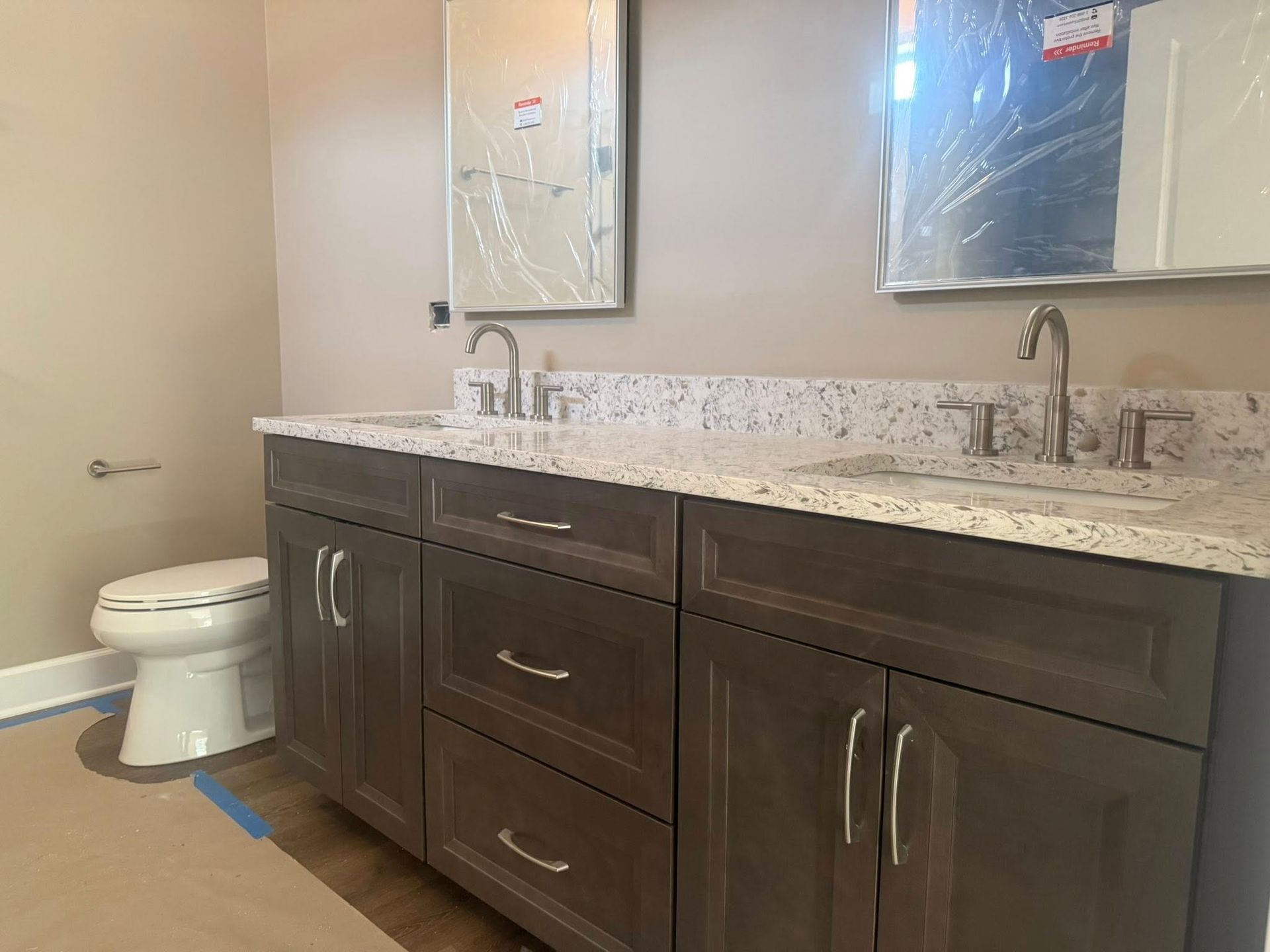 Bathroom with double sink vanity, toilet, and mirrors; cabinets are dark brown.