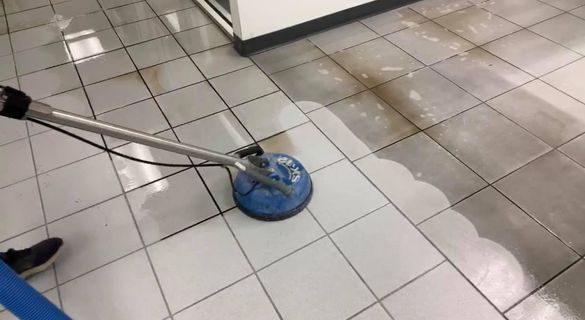 a person is cleaning a tiled floor with a vacuum cleaner
