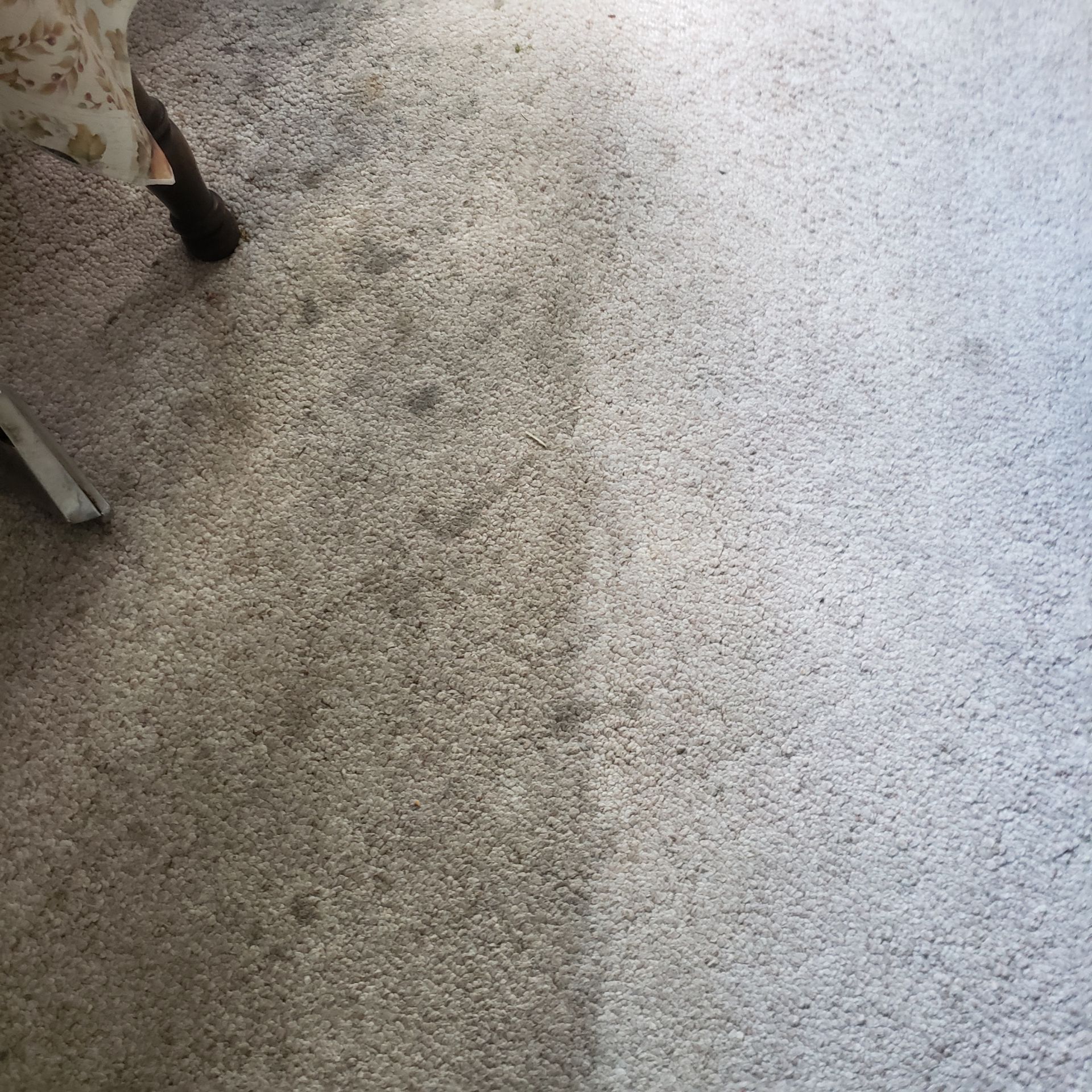 a close up of a carpet with a chair in the background