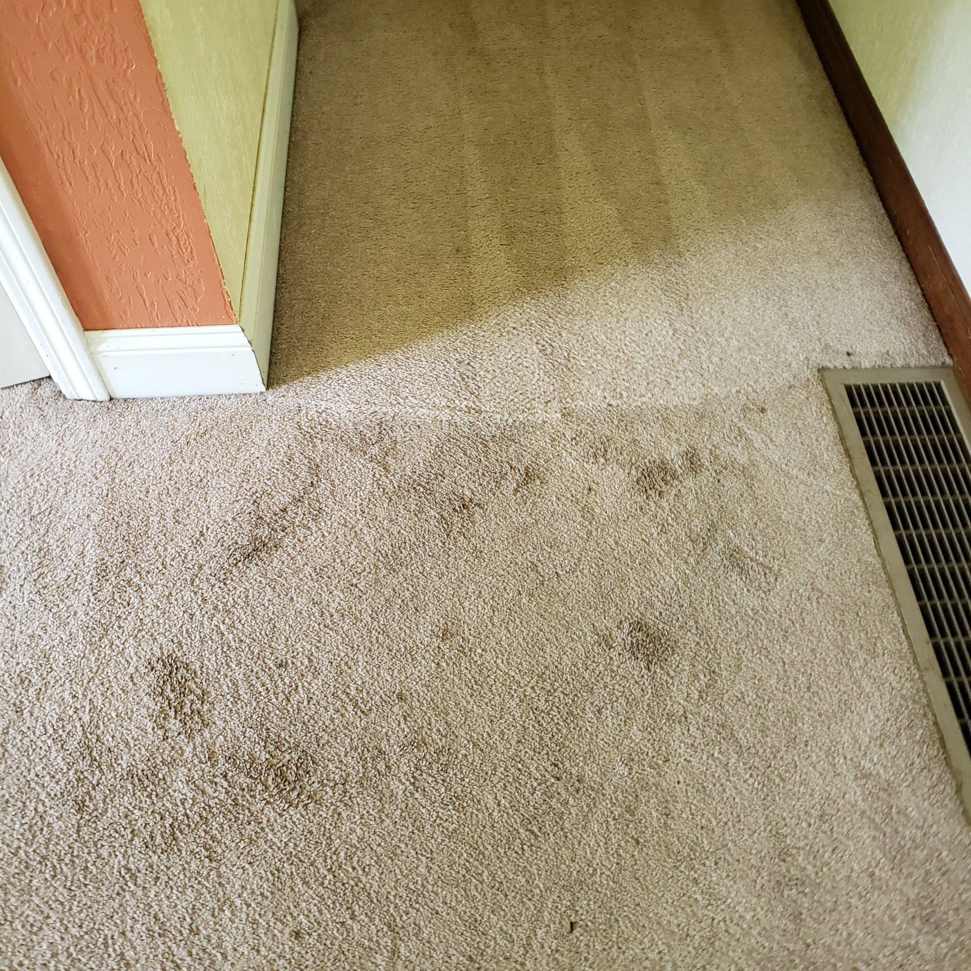 a room with a dirty carpet and a vent on the floor