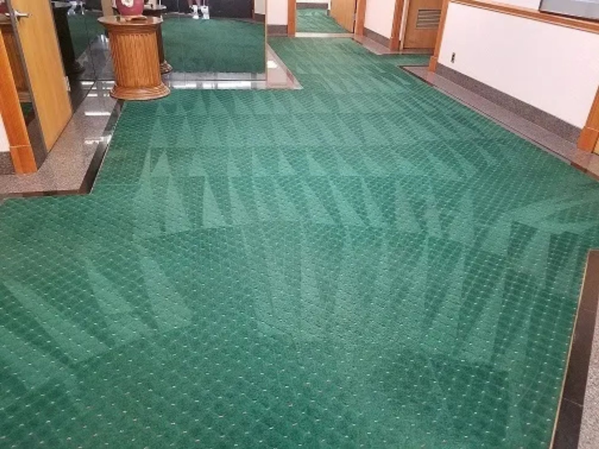a long hallway with a green carpet on the floor
