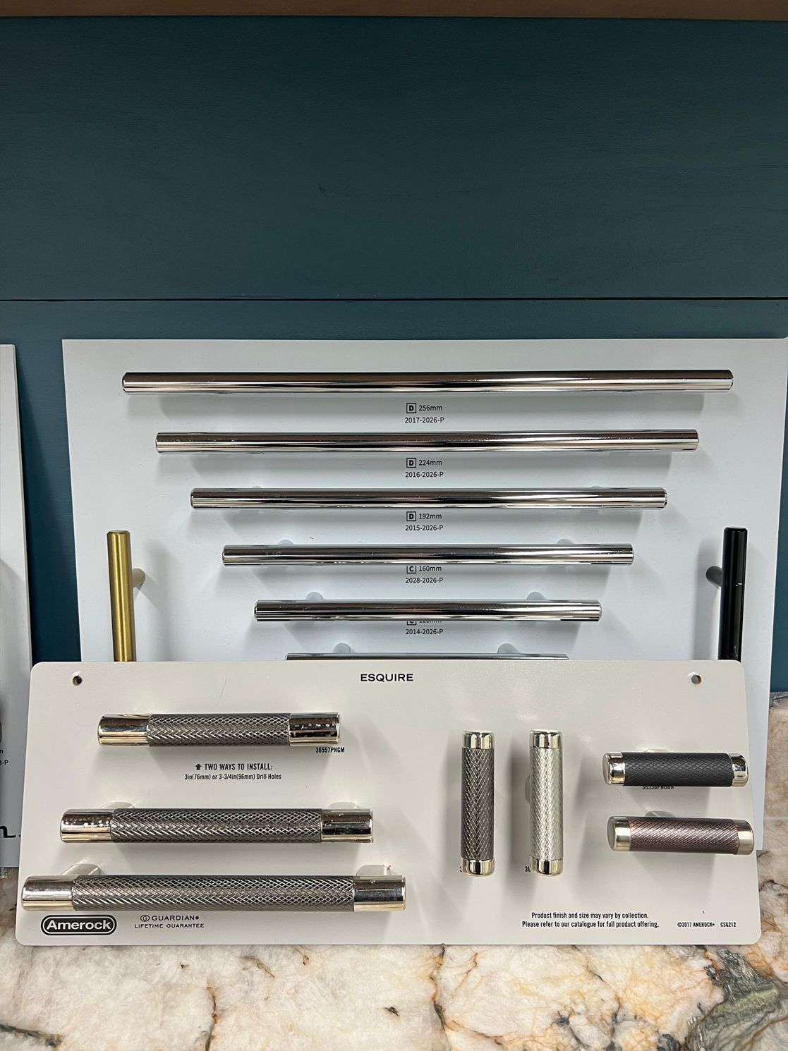 Display of cabinet handles in various styles: silver, gold, and textured black.