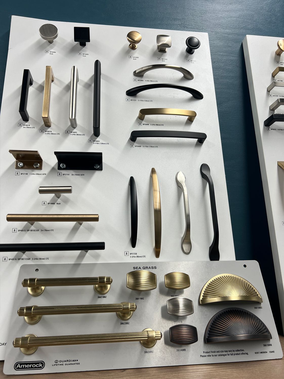Cabinet hardware display board with various knobs and pulls in different styles and finishes.