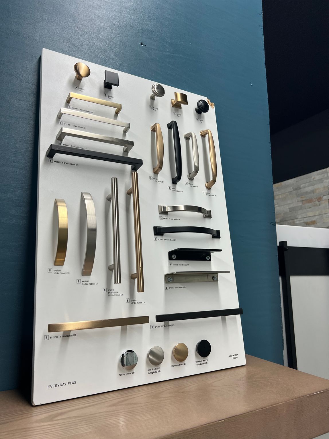Display board with various cabinet pulls and knobs in gold, black, and silver finishes.