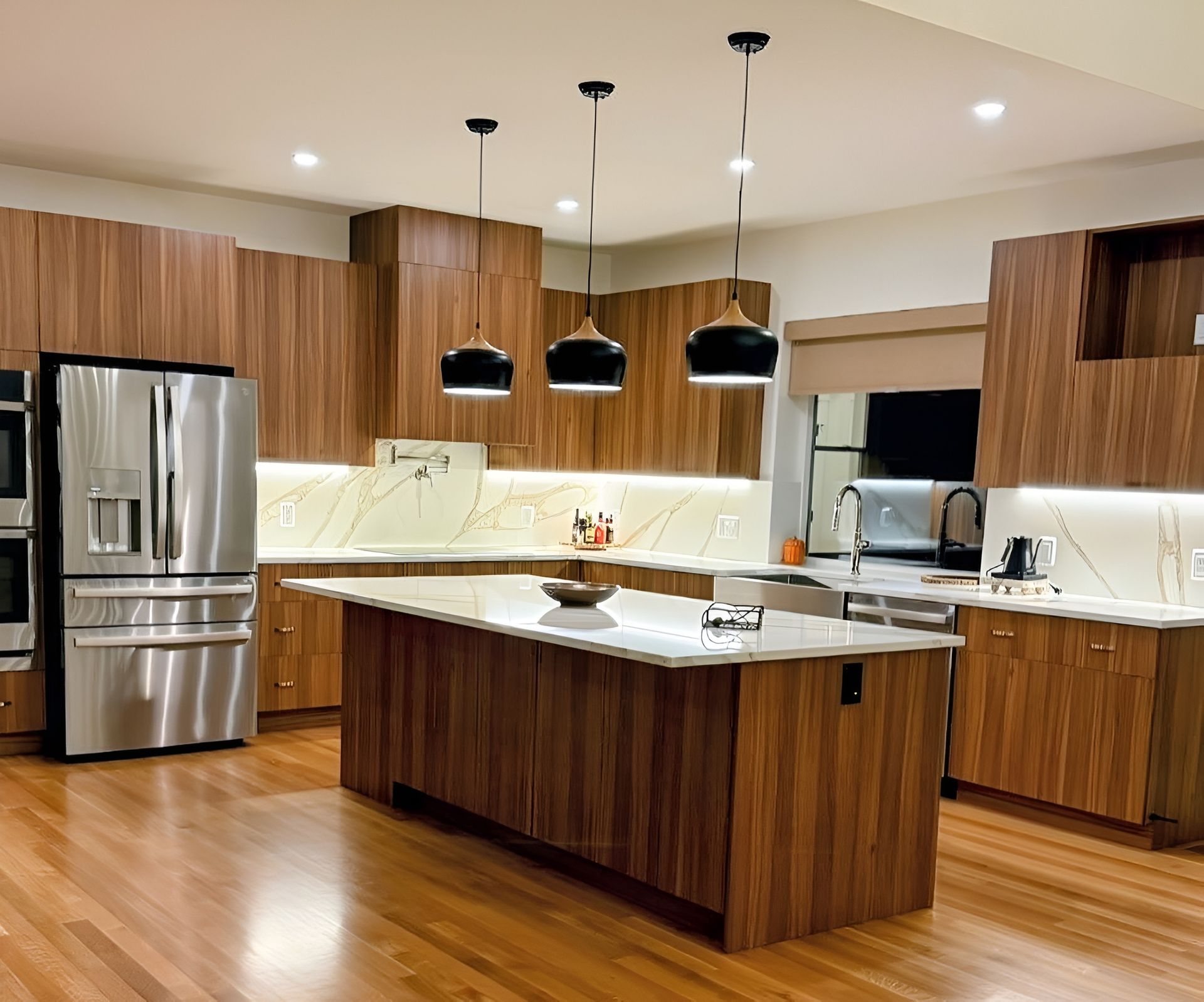 Modern kitchen with wooden cabinets, stainless steel appliances, and island with pendant lights.